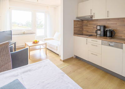 Unterkünfte auf Baltrum: Neue Einbauküche, Esstisch und Wohnzimmerbereich mit Balkon