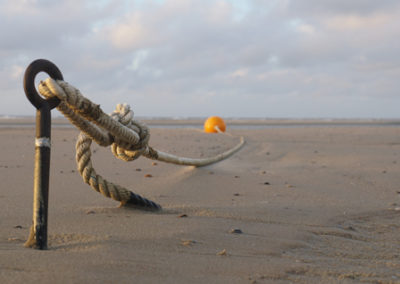 Einzelne orangene Boje am Strand