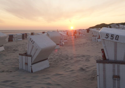 Weiße Strandkörbe am Strand von Baltrum bei Sonnenuntergang